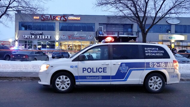 Un véhicule de patrouille du Service de police de la Ville de Montréal est garé devant un édifice où la police est intervenue pour une agression armée.