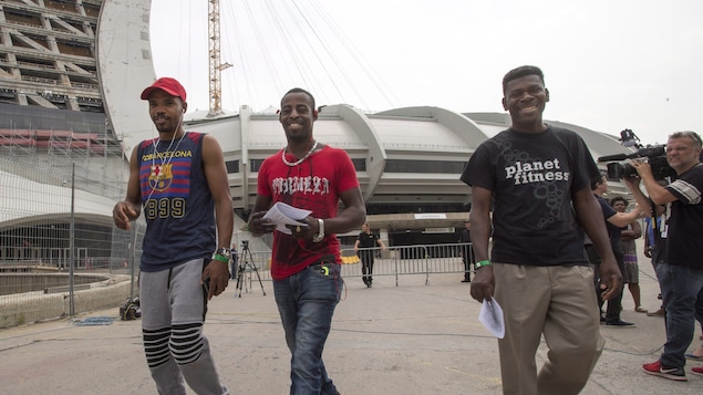 Trois hommes souriant sortent du stade olympique. Trois hommes souriant sortent du stade olympique.