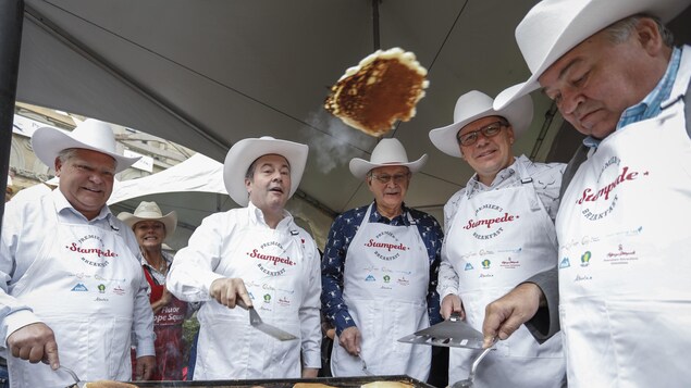 Cinq hommes qui portent des chapeaux de cowboy font cuire des crêpes.