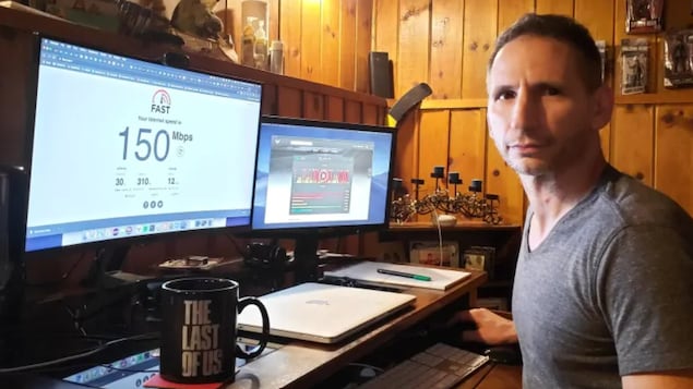 Un homme installé à son bureau à la maison devant un écran d'ordinateur qui affiche 150 Mbps.