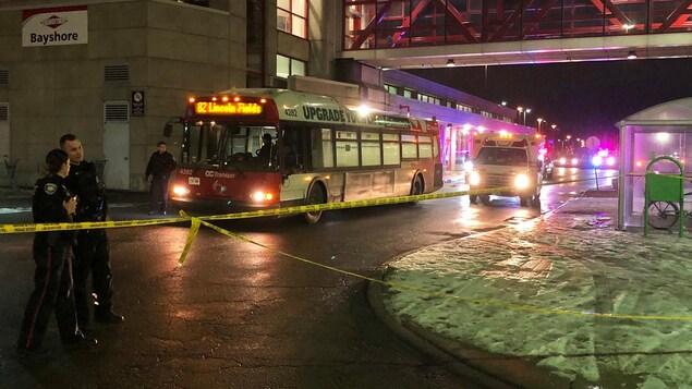 Un autobus d'OC Transpo et des policiers la nuit à la station Bayshore.