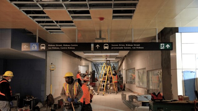 Des travailleurs de construction en action dans un couloir de la station Rideau du futur train léger d'Ottawa Des travailleurs de construction en action dans un couloir de la station Rideau du futur train léger d'Ottawa