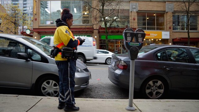Une agente de stationnement vérifie un véhicule dans le quartier Yaletown de Vancouver. Une agente de stationnement vérifie un véhicule dans le quartier Yaletown de Vancouver.