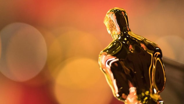 La statuette dorée des Oscars, de dos, dans une lumière orangée