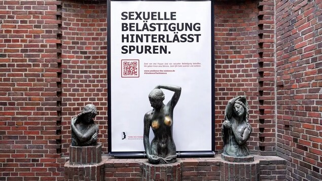 Trois statues de femmes endommagées et l'affiche « Le harcèlement sexuel laisse des traces ». 