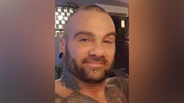 Stephan Joachim est un homme rasé, portant la barbe ainsi qu'un piercing au menton et des boucles d'oreilles de type «stretch».