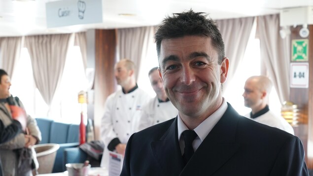 Stéphane Gaudet, commissaire à bord du CTMA Vacancier aux Îles-de-la-Madeleine fait la pose dans le navire devant son équipe de cuisinier.