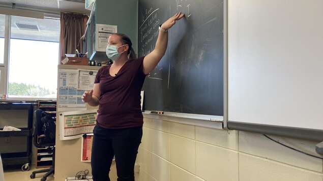 Une enseignante explique un sujet au tableau.