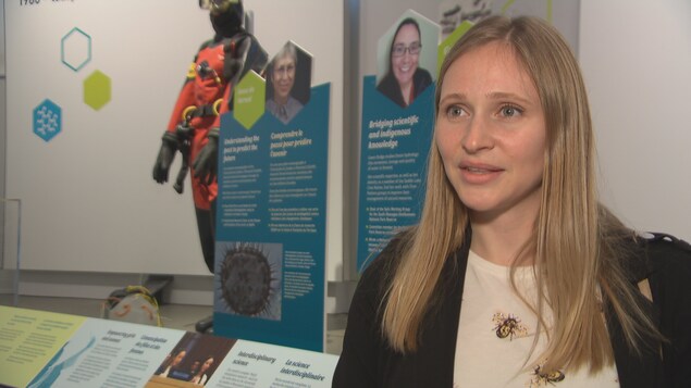 La femme se tient devant des panneaux expliquant les parcours de scientifiques. La femme se tient devant des panneaux expliquant les parcours de scientifiques.