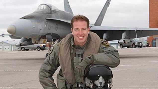 Un homme qui pose devant un avion.