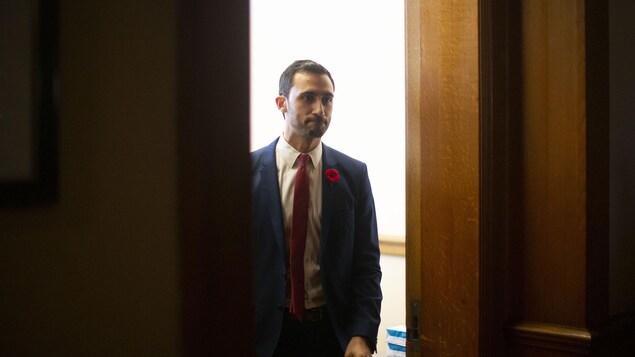 Le ministre de l'Éducation de l'Ontario, Stephen Lecce, sort d'un bureau en se pinçant les lèvres.