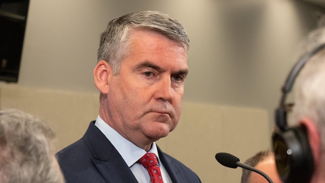 Stephen McNeil entouré de reporters.