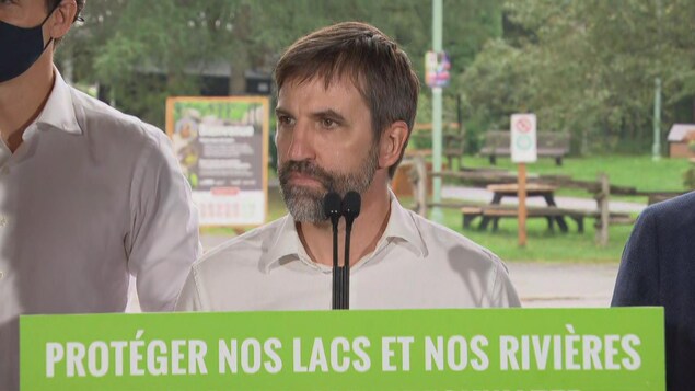 Steven Guilbeault écoute debout derrière un lutrin.