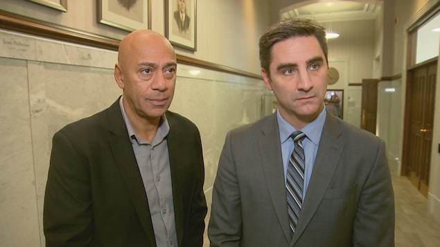 Le conseiller municipal Stevens Melançon (à gauche) et le chef de Québec 21, Jean-François Gosselin (à droite) répondent aux questions du journaliste Olivier Lemieux dans les couloirs de l’hôtel de ville de Québec.