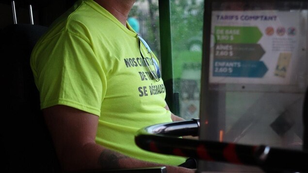 Le chandail d'un chauffeur de la STO où il est inscrit « nos conditions de travail se dégradent. » Le chandail d'un chauffeur de la STO où il est inscrit « nos conditions de travail se dégradent. »