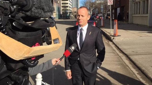 Stockwell Day debout à l'extérieur en entrevue avec la caméra de télévision en avant-plan.