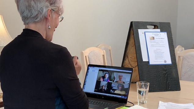 Une femme est en télé-conférence avec trois autres personnes devant son ordinateur.