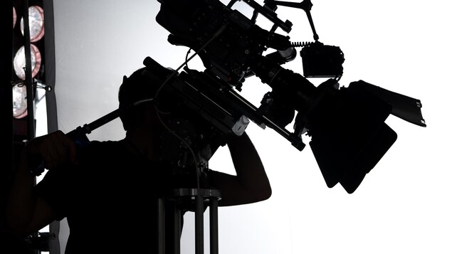 Photo en noir et blanc avec la silhouette d'un opérateur de caméra.