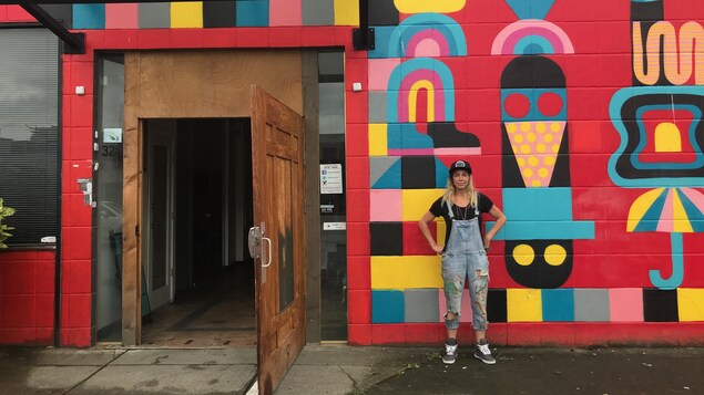 une femem pose devant un mur coloré