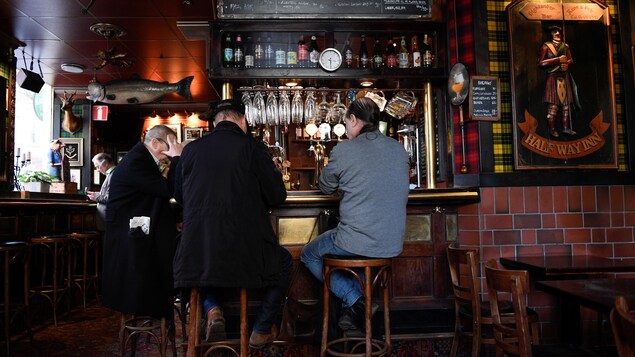 Des gens sont assis au comptoir d’un bar.