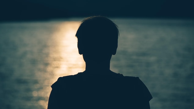 Silhouette d'un jeune déprimé devant un cours d'eau.