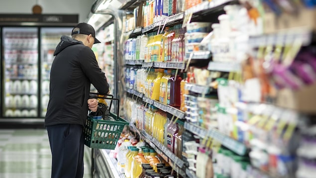 Un homme avec un panier devant un étalage de jus dans une épicerie à Vancouver, le 28 février 2025.