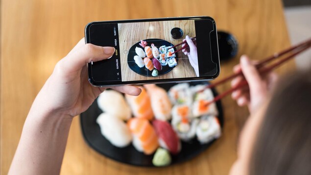 Une femme prend des sushis en photo avec son téléphone intelligent.