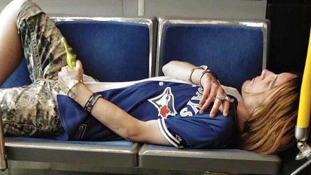 Photo d'un homme couché sur des sièges d'autobus. Il tient une brosse à dents dans une main. Photo d'un homme couché sur des sièges d'autobus. Il tient une brosse à dents dans une main.