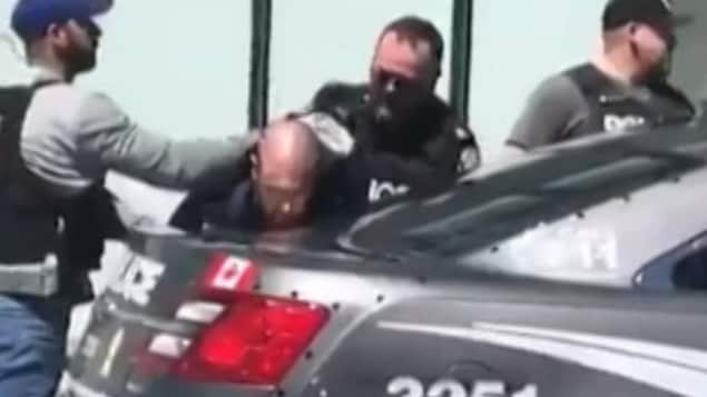 Des policiers de Toronto menottent le suspect contre une voiture.