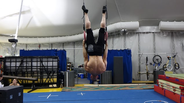 La photo montre un artiste de cirque suspendu avec la tête en bas. La photo montre un artiste de cirque suspendu avec la tête en bas.