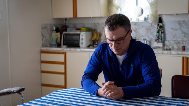 Sylvain Dufour est assis dans la cuisine de sa mère. Il regarde ses mains, qui sont croisées.