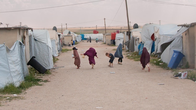 Niños corriendo por un sendero cerca de las tiendas de un campamento.