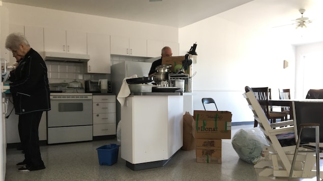 Deux bénévoles installent de articles de cuisine dans l'appartement. Deux bénévoles installent de articles de cuisine dans l'appartement.