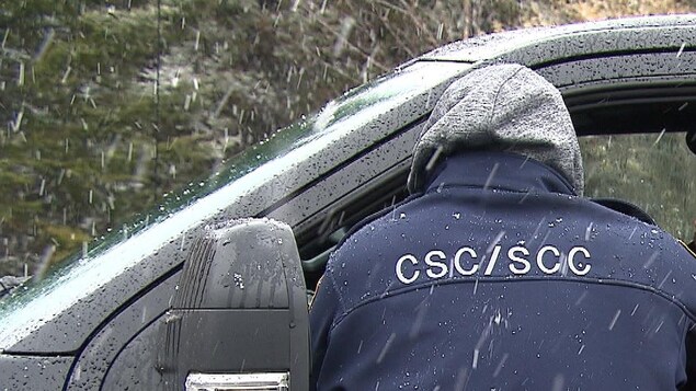Un employé de Service correctionnel du Canada se tient sur le bord du véhicule de l'employé se rendant au travail.