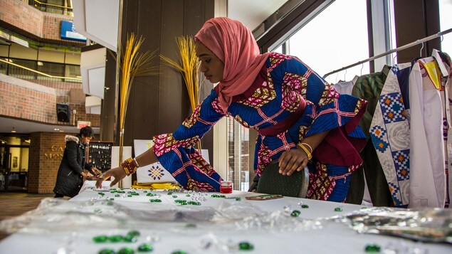 Gaye décore une table avec des pierres colorés pour exposer ses vêtements au public. Gaye décore une table avec des pierres colorés pour exposer ses vêtements au public.