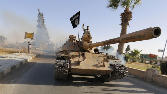 Un militant du groupe armé État islamique sur un tank dans la ville de Raqqa en Syrie en juin 2014