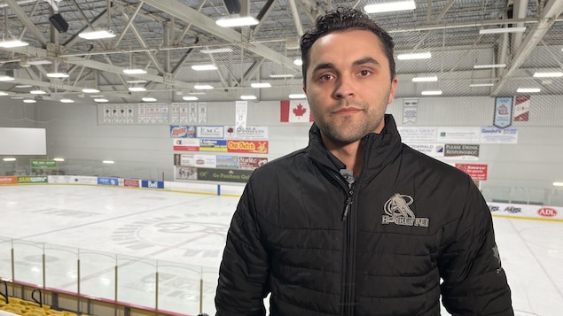 Tanner Doiron regarde la caméra. Il est debout dans des gradins. L'une des patinoires de l'Université de l'Île-du-Prince-Édouard est derrière lui.