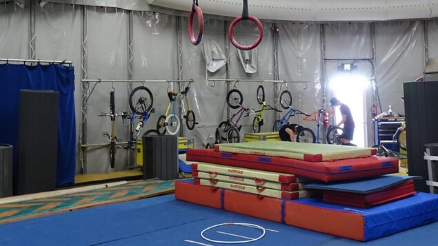 Le photo montre une pile de tapis d'entraînement placés sous des anneaux de voltige. Le photo montre une pile de tapis d'entraînement placés sous des anneaux de voltige.