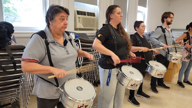 Marie-Josée Tardif et des membres de chez Comsep jouent du tambour.