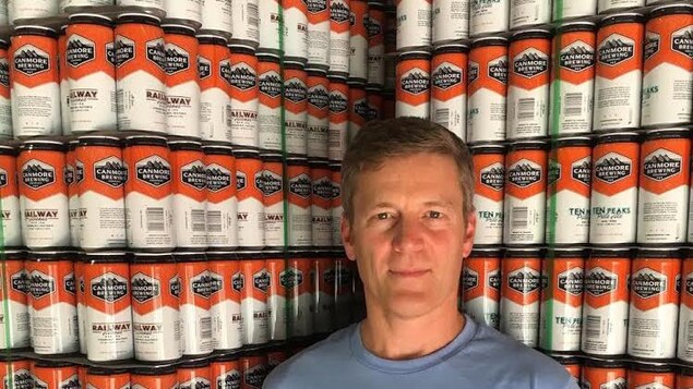 Le PDG Brian Dunn pose devant un mur de canettes de bière de sa brasserie Canmore Brewing Company.