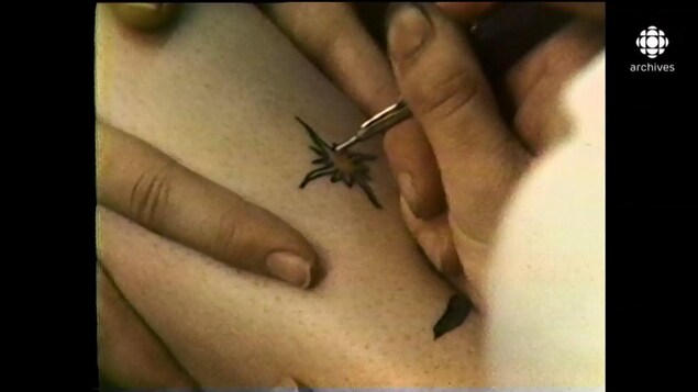 Gros plan sur la main d'une tatoueuse en train de faire un tatouage. 