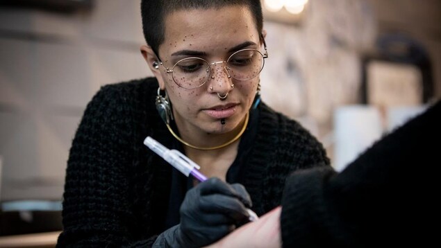 Une jeune femme en pleine séance de tatouage.