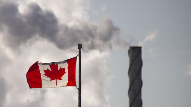 Photo: Radio-Canada / Ivanoh Demers
Un drapeau canadien avec, en arrière-plan, de la fumée qui sort d'une cheminée.