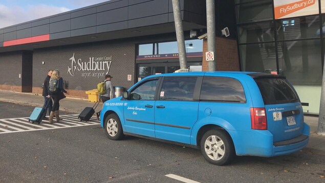 Un taxi bleu est stationné devant l'entrée de l'aéroport de Sudbury. Un taxi bleu est stationné devant l'entrée de l'aéroport de Sudbury.