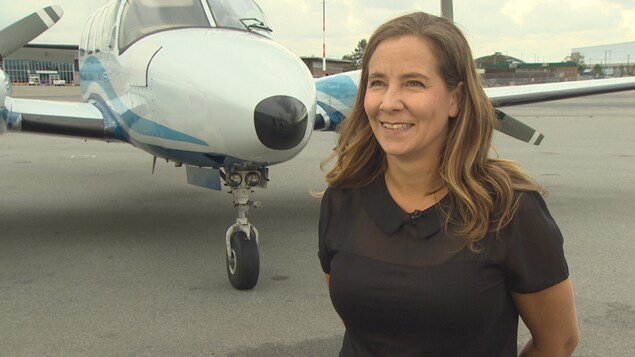 Plan moyen de Teara Fraser souriante devant son avion. Plan moyen de Teara Fraser souriante devant son avion.