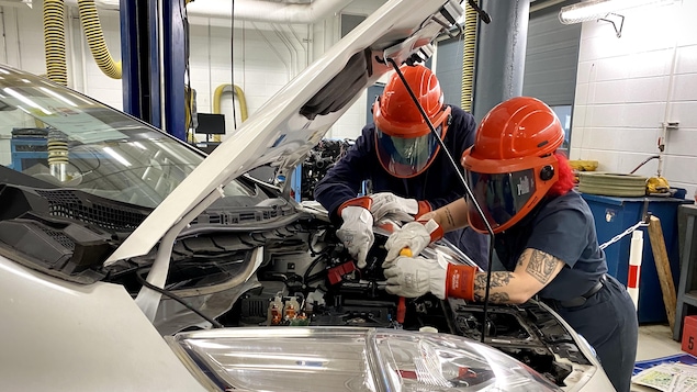 Deux élèves en train de travailler sur le moteur d'une voiture électrique.
