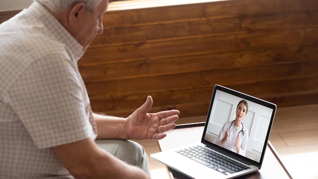 Une homme âgé parle à une spécialiste de la santé lors d'une consultation en ligne.