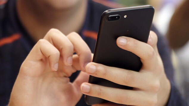 Une personne compose un numéro sur son cellulaire.