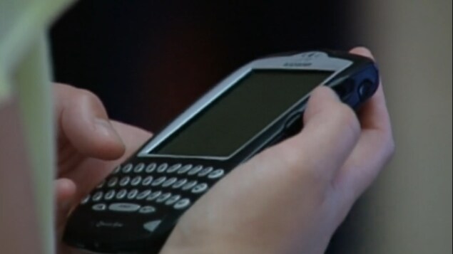 Téléphone BlackBerry avec clavier physique dans une main.