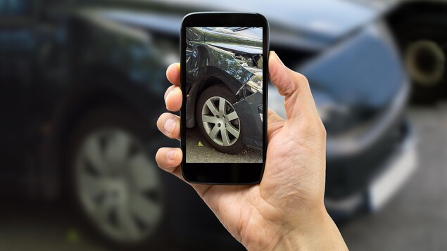 Une auto accidentée sur l'écran d'un téléphone cellulaire tenu par un homme. Une auto accidentée sur l'écran d'un téléphone cellulaire tenu par un homme.